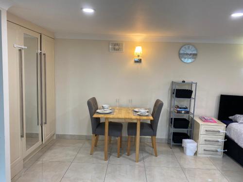 a dining room with a table and chairs and a bed at Studio flat Gants Hill with Free Parking in Redbridge