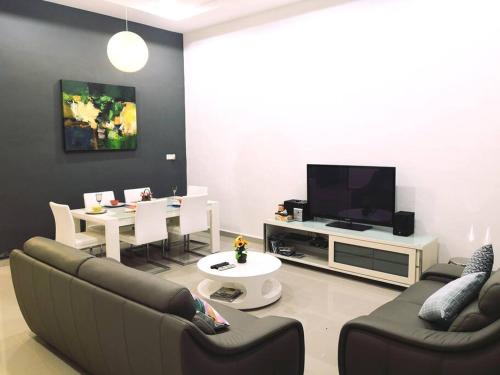 uma sala de estar com dois sofás e uma mesa e uma televisão em Modern COZY HOUSE 3 ROOM 6PAX@ ALMA JUSCO.BM em Bukit Mertajam