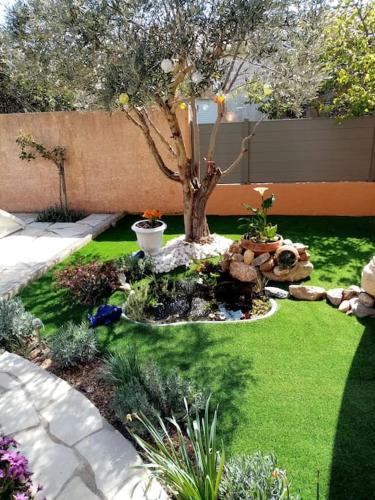 a garden with a tree in the middle of a yard at Appartement calme dans villa, piscine et spa et mer in Portiragnes