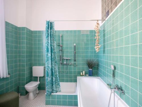 a green tiled bathroom with a tub and a toilet at Ostseevilla Eckernförde in Eckernförde