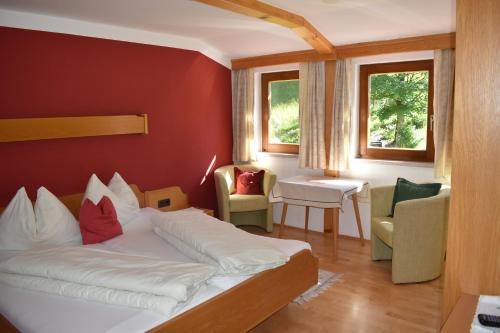 ein Schlafzimmer mit einem Bett und Stühlen in einem Zimmer in der Unterkunft Pension Glöshof in Ramsau am Dachstein