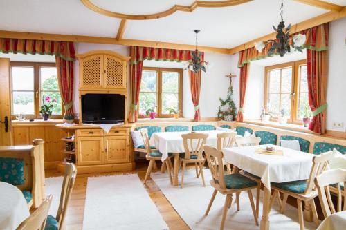 una sala da pranzo con tavoli, sedie e TV di Pension Glöshof a Ramsau am Dachstein