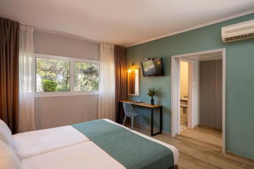 a hotel room with a bed and a desk and a window at Jacob Ohalo Kinneret in Kinneret