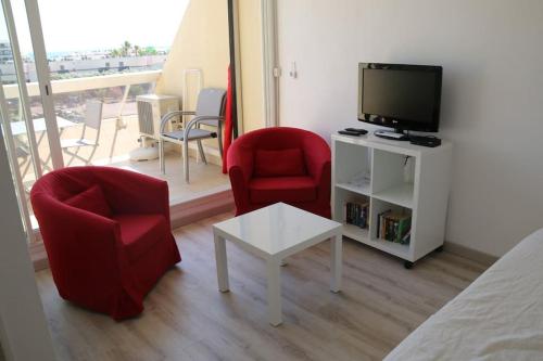 Cette chambre dispose de 2 chaises, d'une télévision et d'une table. dans l'établissement Studio 99, Héliopolis E au village naturiste, au Cap d'Agde