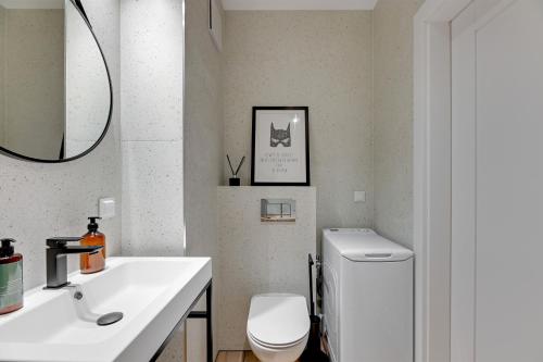 a bathroom with a white toilet and a sink at Downtown Apartments Garnizon in Gdańsk