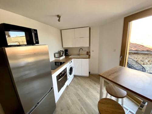 une cuisine avec un réfrigérateur en acier inoxydable et une table dans l'établissement Chaleureux T3 avec terrasse/ Proche Valence, à Saint-Péray
