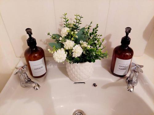 a bathroom sink with two bottles and a vase of flowers at Warm & Cozy 2-Br Apartment. 10 mins from City Centre in Nairobi