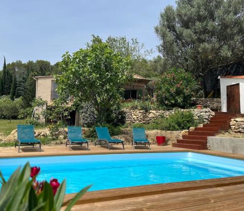 une piscine avec des chaises bleues et une maison dans l'établissement Villa provençale Les Figuiers 3 étoiles - Piscine chauffée, à Lorgues