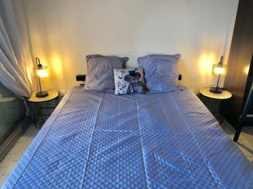 - une chambre avec un lit bleu et deux lampes dans l'établissement Studio 318, Port Vénus au village naturiste, au Cap d'Agde