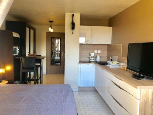 une cuisine avec des armoires blanches et une télévision à écran plat dans l'établissement Studio 318, Port Vénus au village naturiste, au Cap d'Agde