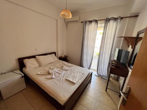 1 dormitorio con 1 cama con sábanas blancas y TV en Lerna Rooms en Míloi