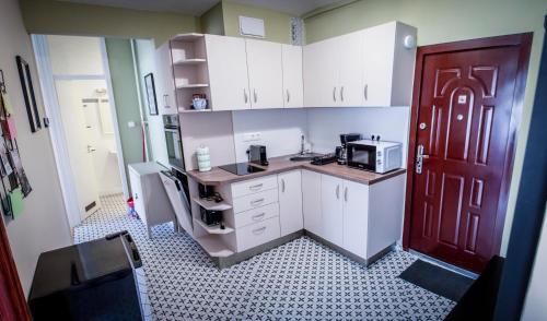 a kitchen with white cabinets and a red door at Centergom in Esztergom