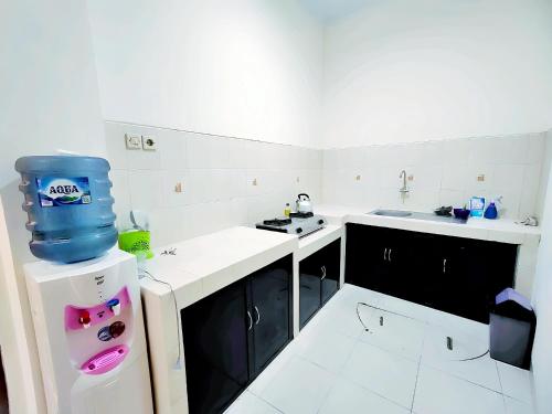 日惹的住宿－De Patuk Homestay，白色的厨房,冰箱顶部有蓝色的桶