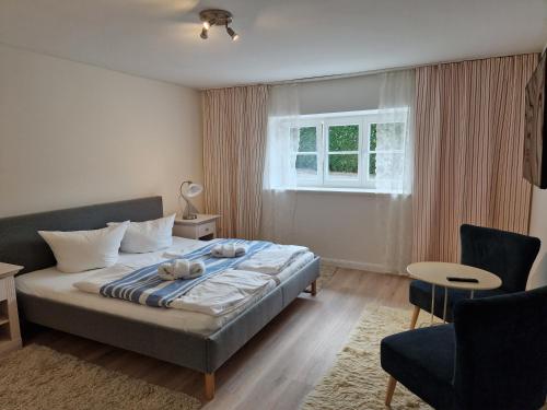 een slaapkamer met een bed, een stoel en een raam bij Ferienwohnung Düne mit Kamin und 2 Bädern in Boltenhagen in Boltenhagen