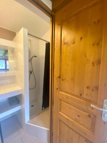 La salle de bains est pourvue d'une douche et d'une porte en bois. dans l'établissement Grenier savoyard, à Verchaix