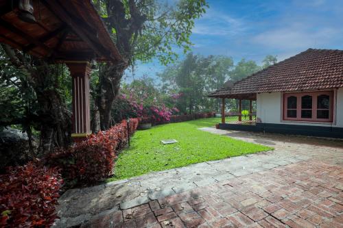 a house with a garden and a brick driveway at Prakruthi Home Stay in Sollebail