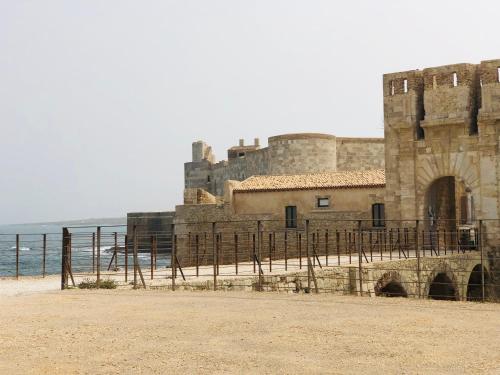 a castle on the beach next to the ocean at I Cinque Mori DEVA in Siracusa