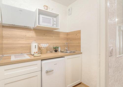 a small kitchen with white cabinets and a sink at LOUISE - Studio de qualité et très cozy in Saint-Étienne