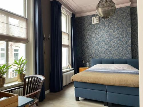 a bedroom with a blue bed and two windows at Bed & Breakfast By Genck in Oudenbosch