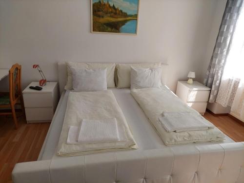 ein großes weißes Bett in einem Raum mit zwei Tischen in der Unterkunft Weißes Appartement in Wien