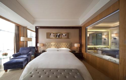 a bedroom with a large bed and a blue chair at Sheraton Changzhou Xinbei Hotel in Changzhou