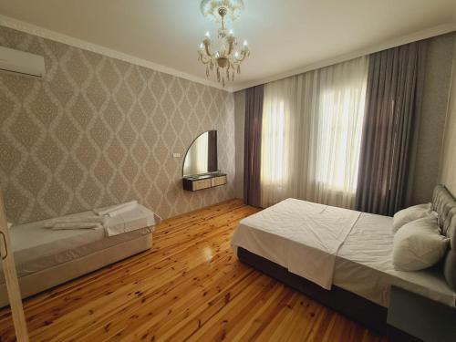 a bedroom with two beds and a chandelier and wooden floors at Yasin White villa in Gabala