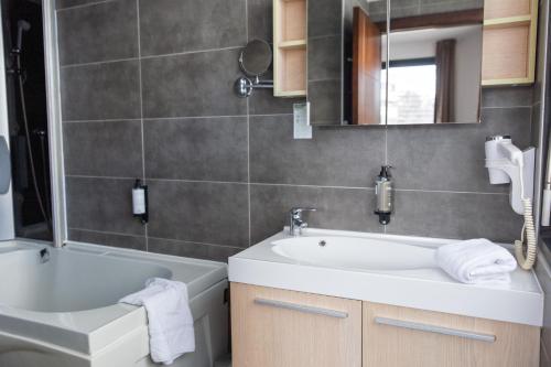 a bathroom with a sink and a tub and a mirror at Zenitude Swiss Apparthotels in Ferney-Voltaire