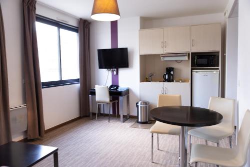 a living room with a table and a kitchen at Zenitude Swiss Apparthotels in Ferney-Voltaire
