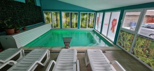 - une piscine avec des chaises blanches et une piscine dans l'établissement Pensiunea Mama Uta, à Gîrda de Sus