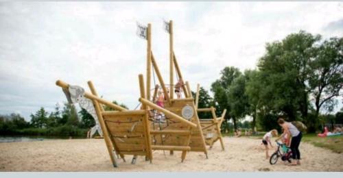 a group of wooden playground equipment on a beach at VakantieNoord, chalet 6p with veranda, located in Friesland, 5 stars camping on the lake in Suameer