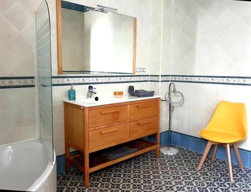 baño con lavabo, espejo y silla amarilla en La Casona de Alba, en Encinasola