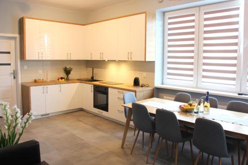 a kitchen with white cabinets and a table and chairs at APART MAZURY Apartamenty na Mazurach in Orzysz