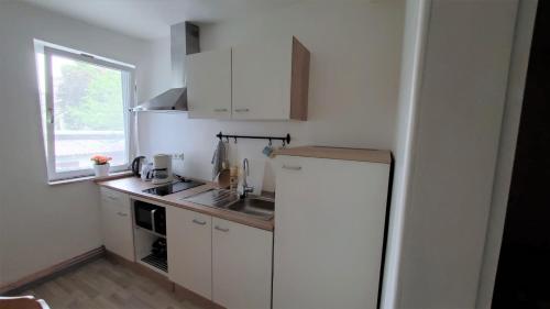 a small kitchen with a refrigerator and a window at Landgasthof Steuber - Hotel garni in Bromskirchen