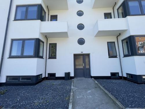 an empty white building with a black door at aday - Northern light apartment in Frederikshavn