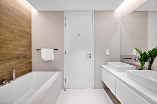 a white bathroom with two sinks and a tub at VayK - Spacious One Bedroom with Ain Views in Dubai