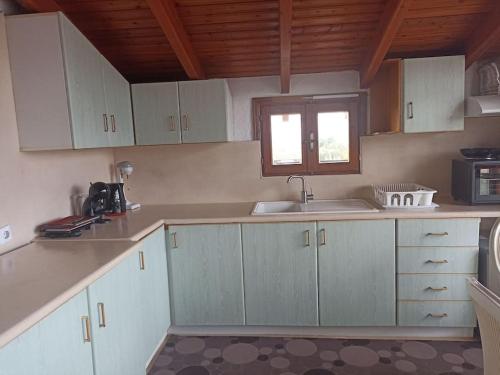 a kitchen with white cabinets and a sink and a window at Cozy house in Tagarades