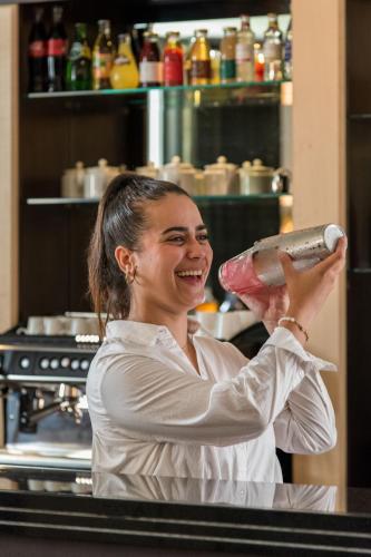 a woman holding up a bottle in a kitchen at Zenitude Hotel la Valadière, an Ascend Collection Hotel in Montpellier