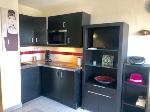 - une cuisine avec des placards noirs et un évier dans l'établissement Studio 322, Port Vénus au village naturiste, au Cap d'Agde