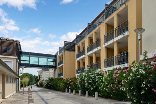 an apartment building with flowers and a walkway at Zenitude Hotel la Valadière, an Ascend Collection Hotel in Montpellier
