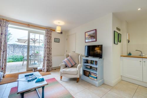 a living room with a tv and a chair at Little Scarlet in East Dean
