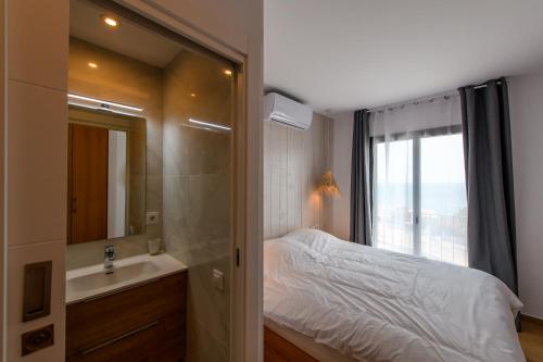 een slaapkamer met een bed, een wastafel en een spiegel bij Can Bailet in Cadaqués