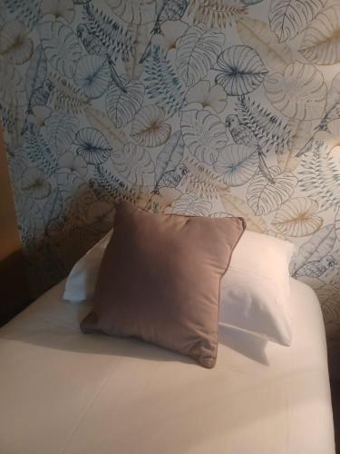 a bed with a pillow in front of a wall at Hôtel La Parenthèse in Attignat
