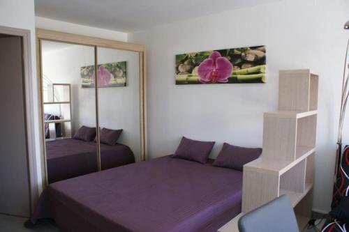 une chambre avec un lit violet et un miroir dans l'établissement Studio 52, Héliopolis E au village naturiste, au Cap d'Agde