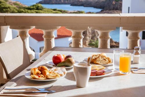 een tafel met borden ontbijtproducten op een balkon bij Seth Sa Mirada in Arenal d'en Castell