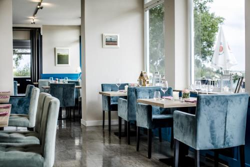 un restaurante con sillas azules, mesas y ventanas en Hotel Fährhaus km734, en Düsseldorf