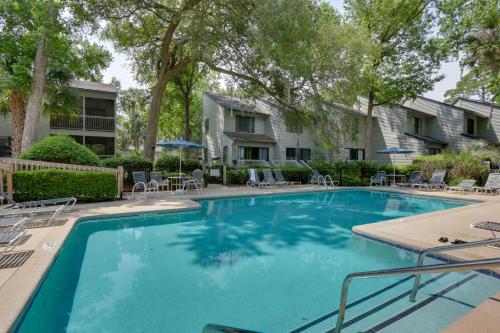 a large swimming pool with chairs and trees at Serene Hilton Head Island Condo with Community Pool! in Hilton Head Island