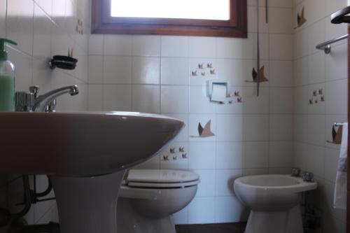 Un baño con lavabo, inodoro y ventana. en Belvedere mare e pineta, en Lido di Ostia