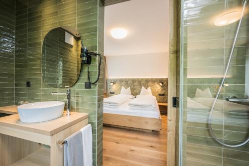 a bathroom with a sink and a shower and a bed at Gasthof Albergo Dolomiten in Braies