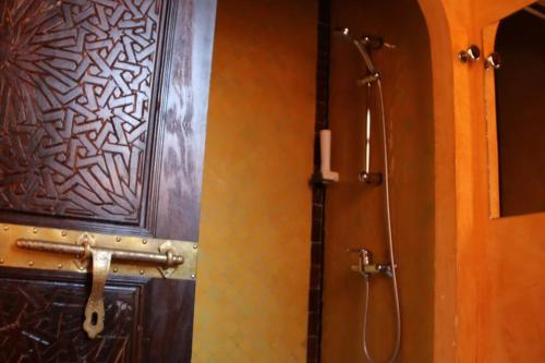 ein Badezimmer mit einer Dusche und einer Holztür in der Unterkunft Chambre Merzouga, Riad 8 au village naturiste Couple only in Cap d'Agde