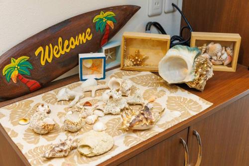 a table with shells and a surfboard on it at 庭付き一棟貸 ビーチまで3分 宇利島車で7分 最大8人 Luana house in Nago